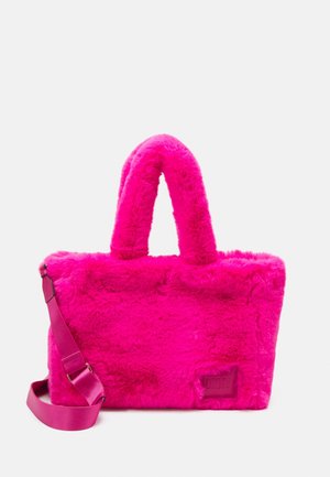 Helles pinkfarbenes, flauschiges Handtäschchen mit zwei kurzen Henkeln und einem verstellbaren langen Riemen vor einem schlichten hellen Hintergrund.