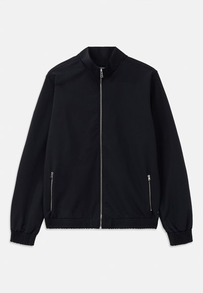 Fekete dzseki álló gallérral, elülső cipzárral, oldalsó zsebekkel és rugalmas mandzsettákkal. Sima anyag, minimalista dizájnnal.