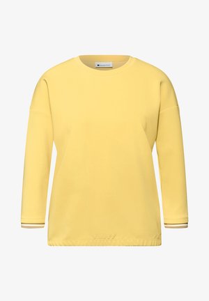 Camiseta amarilla de manga larga con cuello redondo, hombros caídos y puños con sutiles rayas sobre fondo blanco.