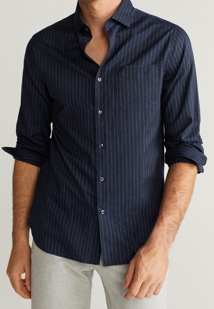 Chemise à rayures bleu marine avec manches longues, col boutonné, poche poitrine et manches retroussées, fabriquée dans un tissu léger.