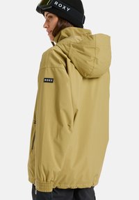 Rumena vodoodporna jakna s kapuco, stranskimi žepi, elastičnimi manšeti in logotipom na rokavu. Gladka tekstura in sproščen kroj.