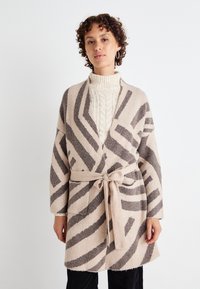 Beige és szürke mintás, hosszú ujjú, övvel és zsebekkel ellátott kardigán; puha, texturált anyagból készült.
