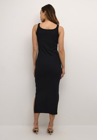 Black, sleeveless midi dress featuring a form-fitting design, side slit, and smooth texture. Minimalist, with a rounded neckline.