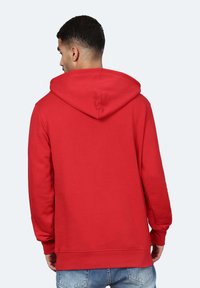 Felpa rossa con cappuccio e maniche lunghe, dotata di tasca a marsupio e polsini a costine. Texture liscia e vestibilità rilassata.