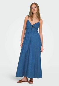 Denimska maxi haljina s V-izrezom, detaljem za vezanje sprijeda i trakicama. Haljina ima slobodan kroj i jedinstvenu plavu boju.