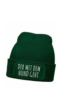 Green knitted beanie featuring a ribbed texture and a fold-over cuff with a rectangular patch displaying the text "DER MIT DEM HUND GEHT."