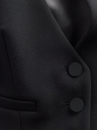 Μαύρο σακάκι χωρίς μανίκια με υφή υφάσματος, που διαθέτει δύο στρογγυλά μαύρα κουμπιά, κομψό πέτο και κρυφή λεπτομέρεια τσέπης.