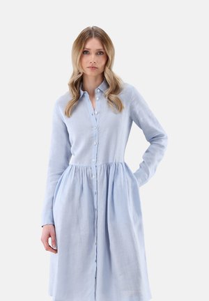 Helles blaues Hemdkleid mit langen Ärmeln, gerafftem Bund und fließendem Rock, aus einem weichen, strukturierten Stoff gefertigt.