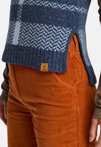 Blauwe gebreide trui met patroon en ribbelzoom, gecombineerd met oranje corduroy broek met een gestructureerd oppervlak en Timberland logo label.
