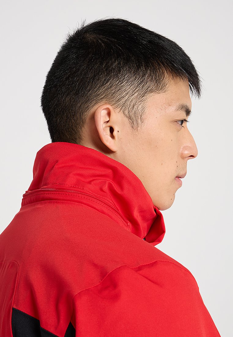 Rote Fleecejacke mit hohem Kragen, featuring einen Reißverschluss und schwarzen Akzenten an den Seiten. Glatte Textur, leichtes Design.