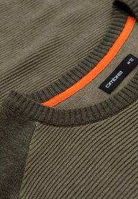Maglione verde oliva con texture, collo a costine e accentuazione arancione sul colletto. Presenta l'etichetta del marchio "ombre" e un design elegante.