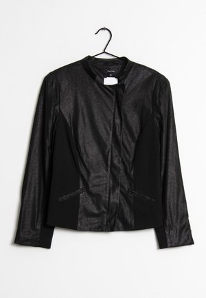 Blazer noir pour femme à manches longues avec un léger éclat, col rond et détails de coutures avant, suspendu à un cintre noir sur fond blanc.