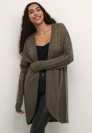 Cardigan lavorato a maglia verde oliva con un motivo testurizzato, aperto davanti e maniche lunghe, indossato sopra un top nero e pantaloni di pelle.