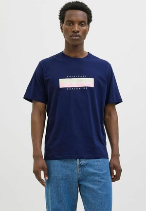 Marineblå bomulds t-shirt med et rektangulært grafik, der viser teksten "Jack & Jones Originals Worldwide" i pink og hvid. Korte ærmer.