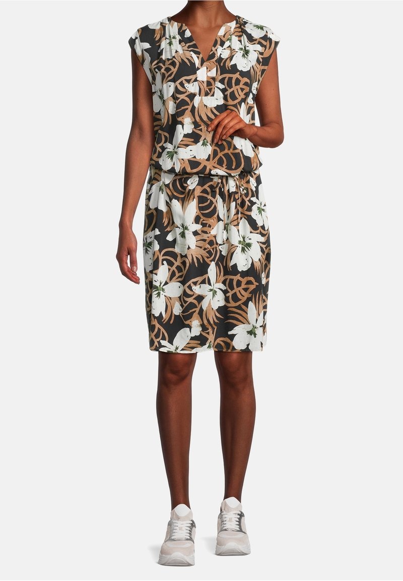 Blommig klänning med korta ärmar, svart bakgrund, vit och brun blommig tryck, midjehöjd, knälängd, bärs med grå sportskor.
