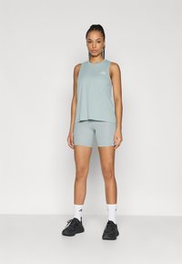 Light green sleeveless athletic top and matching shorts. Fabric appears moisture-wicking. Accented with a subtle logo. Black sneakers complete the outfit.