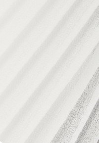 Tissu blanc transparent avec une fine texture tissée et de doux plis verticaux créant des lignes d’ombre subtiles.