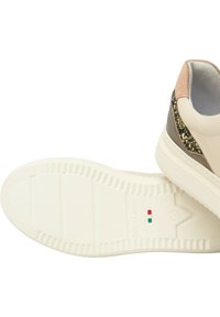 Soletta bianca delle sneaker con battistrada a scanalature, testo "NeroGiardini Made in Italy" e dettaglio della bandiera italiana; la parte superiore mostra accenti beige e glitter.