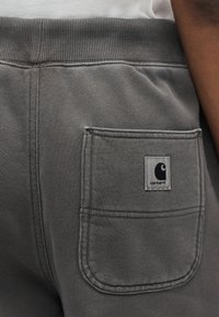 Γκρι παντελόνι φόρμας Carhartt με ελαστική μέση και πίσω τσέπη με ετικέτα λογότυπο Carhartt.