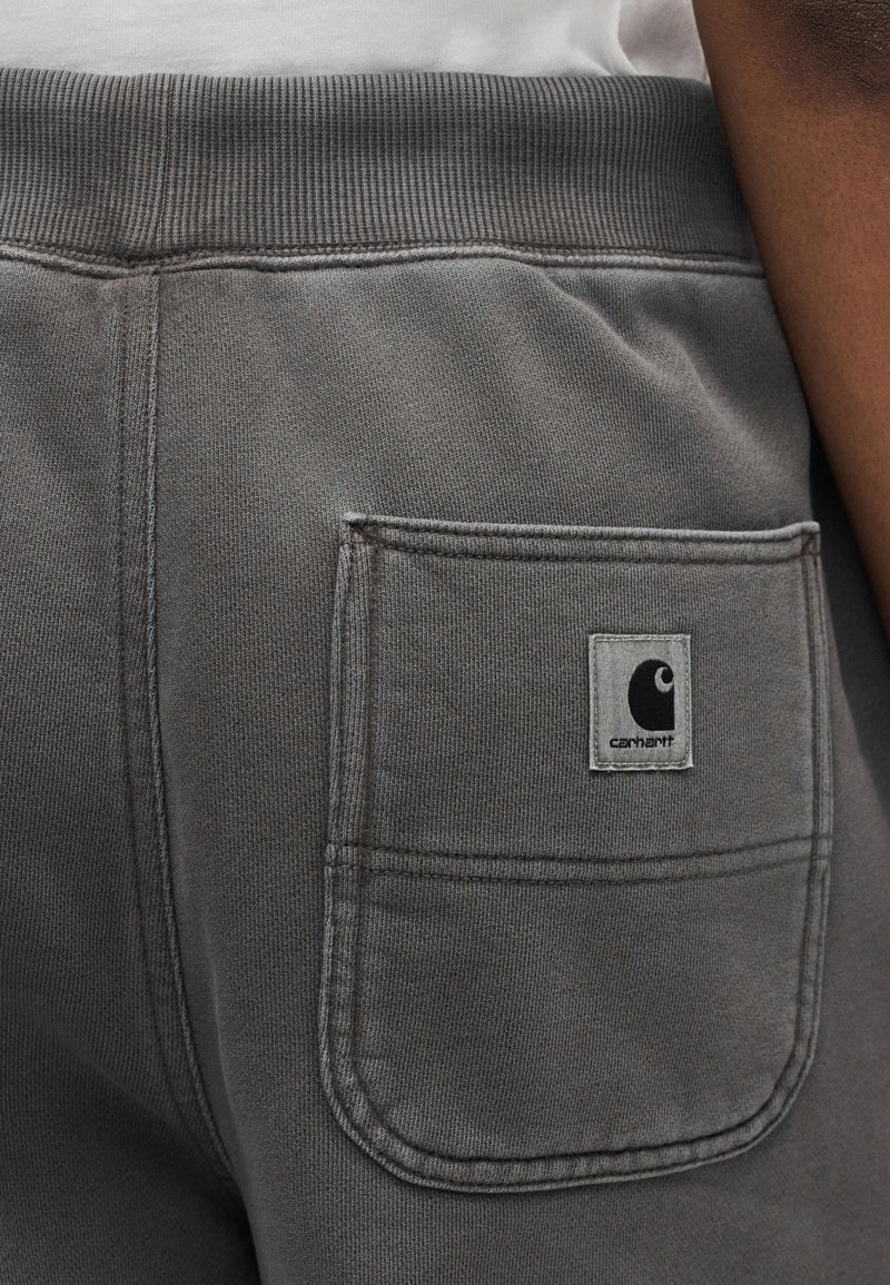 Pantaloni della tuta Carhartt grigi con vita elastica e tasca posteriore con etichetta del logo Carhartt.