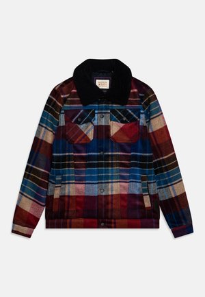 Veste à carreaux avec fermeture à boutons sur le devant, poches poitrine à rabat, poches latérales et col noir dans des tons de bleu, rouge, beige et marron.