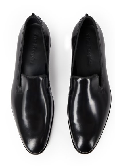 Paire de chaussures habillées élégantes en cuir noir à enfiler, à bouts arrondis, vues de dessus sur fond blanc.