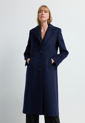 Marineblauwe wollen jas met een notch lapel, een vijfknopen front en zijzakken. Beschikt over op maat gemaakte mouwen en een recht silhouet.