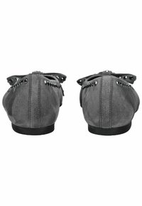 Zapatos planos de ante gris con punta redondeada, adornados con acentos de tachuelas negras a lo largo de los bordes y un lazo en la parte trasera. Suela de goma negra.