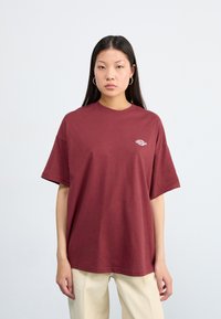 T-shirt oversize bordeaux en coton. Doté d'un col rond et de manches courtes. Petit logo blanc sur la zone du côté gauche de la poitrine.