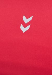 Rode sportieve shirt stof met een gladde textuur; bevat een wit chevron logo ontwerp dat centraal is geplaatst.