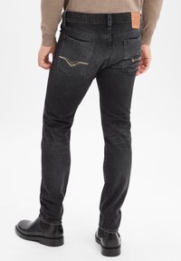 Zwarte denim jeans met een slim fit, voorzien van een tan leren merkpatch, twee achterzakken en een subtiele decoratieve stikselontwerp.