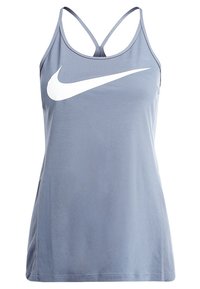 Jasnoniebieski sportowy tank top z cienkimi, skrzyżowanymi ramiączkami. Z przodu widoczny jest duży biały logo Nike w kształcie „swoosh”. Miękka tkanina o gładkiej fakturze.