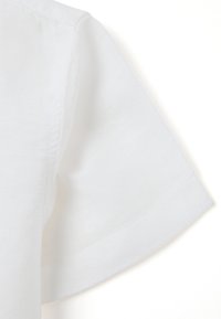 Witte linnen kleding met een brede mouw, een gladde textuur en nette naaddetails, waarmee een zacht, lichtgewicht stofontwerp wordt getoond.