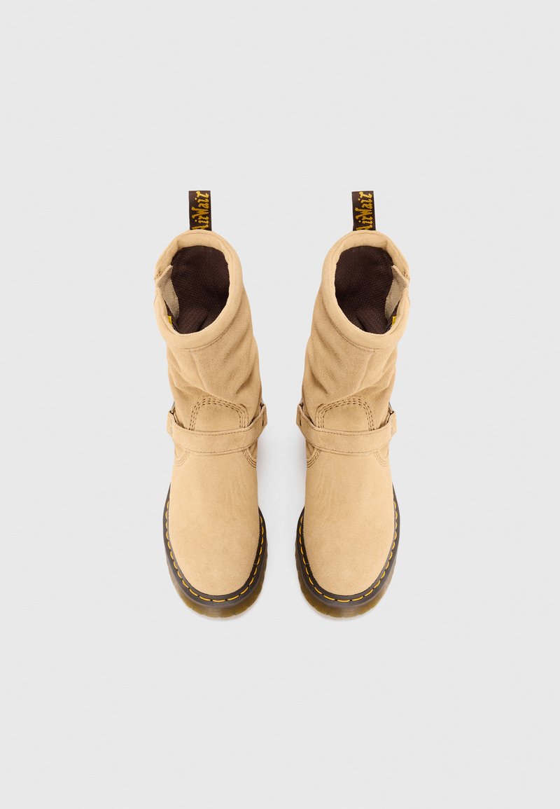 Bottines en daim tan avec un design flou, doublure marron, sangle réglable et couture jaune contrastante autour d'une semelle en caoutchouc noir.