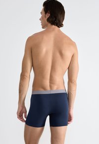 Boxer in blu navy con elastico grigio chiaro, progettati per comfort e vestibilità. Tessuto dalla superficie liscia, design minimalista senza fantasie.