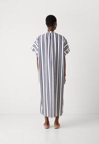Abito maxi a righe in navy e bianco con maniche corte, vestibilità ampia e scollatura arrotondata. Tessuto morbido con righe verticali.
