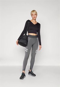 Juodas ilgomis rankovėmis trumpas viršus, marginti pilki leginsai su atspindinčiomis juostelėmis ir juodi sportbačiai; nešiojasi juodą sporto krepšį.