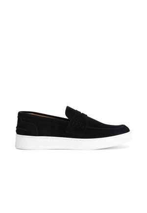 Scarpe slip-on in suede nero con suola in gomma bianca, caratterizzate da un design cucito e un accento testurizzato sulla tomaia.