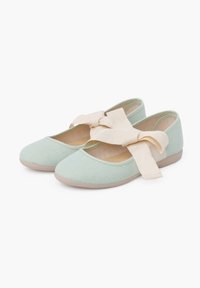 Ballerines en tissu vert clair avec une surface texturée et des accents en ruban beige, dotées d'une semelle basse et flexible et d'un design à bout rond.