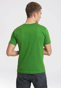 Green cotton t-shirt with short sleeves, crew neck design, smooth texture, and minimal detailing, worn by a person facing away.