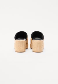 Espadrille plattform sandaler med en vevd jute-bunn og svart tekstiloverside. Har lukket bak og åpen tå-design. Strukturert overflate.