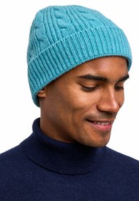 Beanie a maglia blu chiaro con bordo a coste, realizzato in morbida lana, indossato da una persona. Il cappello presenta un motivo testurizzato in tutto.