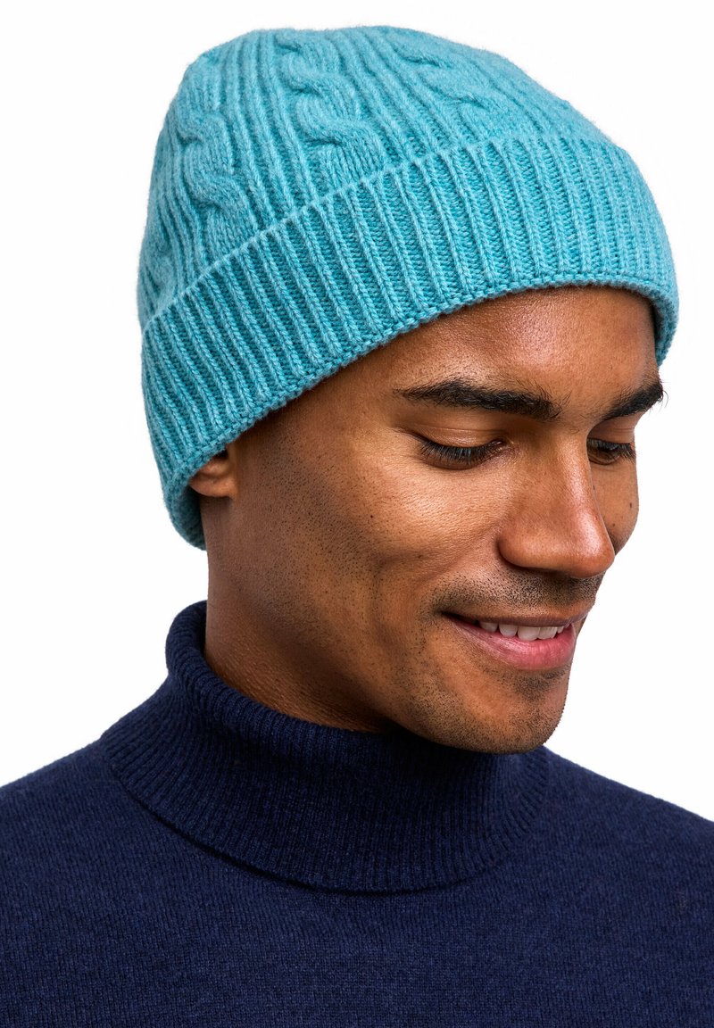 Beanie a maglia blu chiaro con bordo a coste, realizzato in morbida lana, indossato da una persona. Il cappello presenta un motivo testurizzato in tutto.