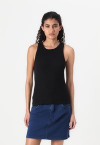 Zwarte mouwloze tanktop met een ronde halslijn, gecombineerd met een blauwe jeansrok met voorzakken en een rechte snit.