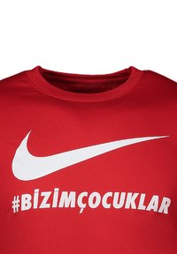 Rode katoenen t-shirt met een wit Nike swoosh-logo en de Turkse hashtag "#BİZİMÇOCUKLAR" gedrukt in vetgedrukte witte tekst op de voorkant.