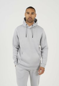 Lichtgrijze hoodie met gestructureerde stof, capuchon met trekkoord en voorzak, gecombineerd met bijpassende broek voor een samenhangende uitstraling.