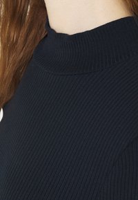 Maglione a collo alto rigato navy con design aderente. Presenta un colletto alto e un tessuto testurizzato, che si estende fino alla zona delle spalle.