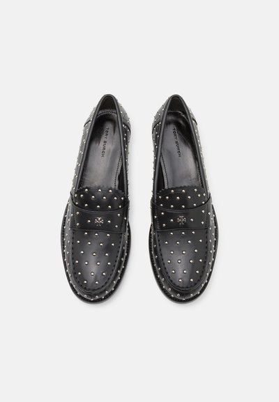 Čierne kožené mokasíny so striebornými cvočkami, hladkým povrchom a dekoratívnym pásikom na prednej strane. Majú okrúhlu špičku a plochú podrážku.