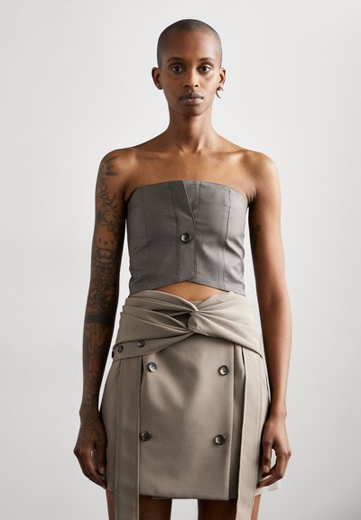 Gray strapless cropped top with structured design and front button detail, paired with a high-waisted beige skirt featuring twisted fabric and buttons.