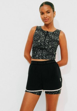 Top corto nero con un intricato motivo bianco, abbinato a pantaloni corti neri con una cintura brandizzata e un rivestimento interno a contrasto.